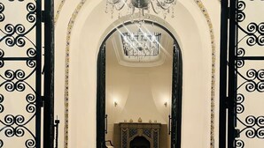 Ein prachtvoller Eingangsbereich mit einem schwarzen schmiedeeisernen Tor, einer Kristallleuchter und einem Kamin.