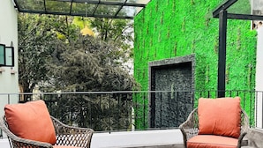 Ein Balkon mit Korbmöbeln, einem runden Tisch und einer grünen, vertikalen Wandbegrünung.