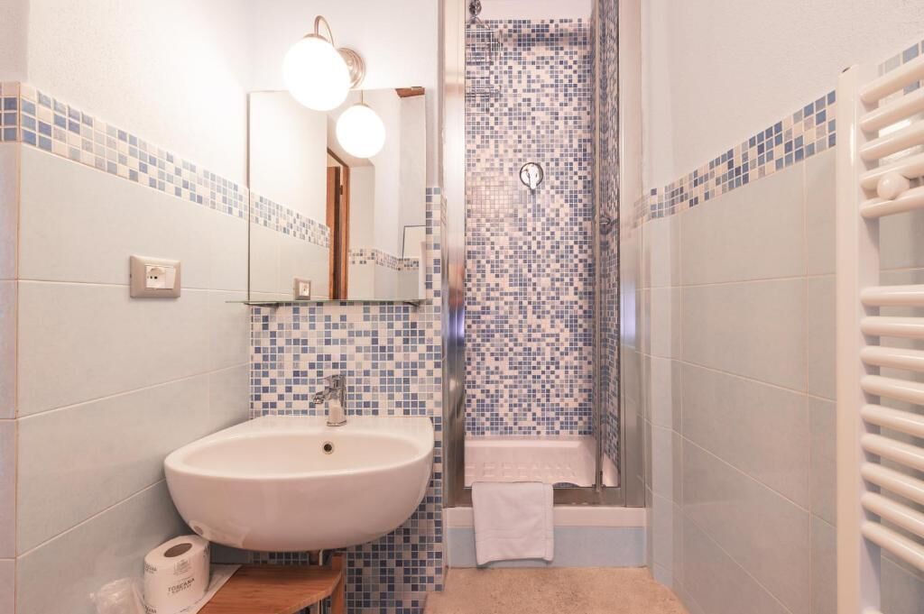 A bathroom with a sink, mirror, and shower.