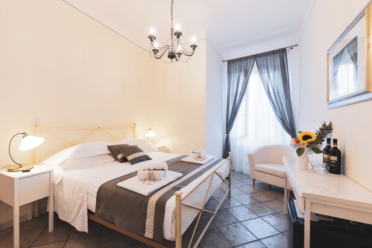 A neatly arranged bedroom with a bed, bedside tables, a desk, and a chair.