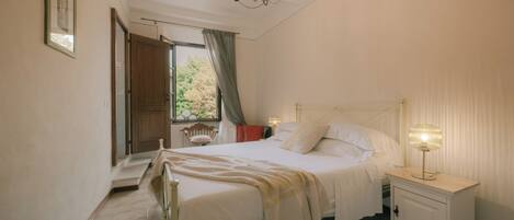 A bedroom with a bed, bedside table, and a chandelier.