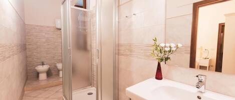 Un baño moderno con ducha a ras de suelo, un bidé y una bañera grande.