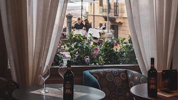 Un restaurante con vistas, con cortinas translúcidas, mesas redondas y cojines estampados.