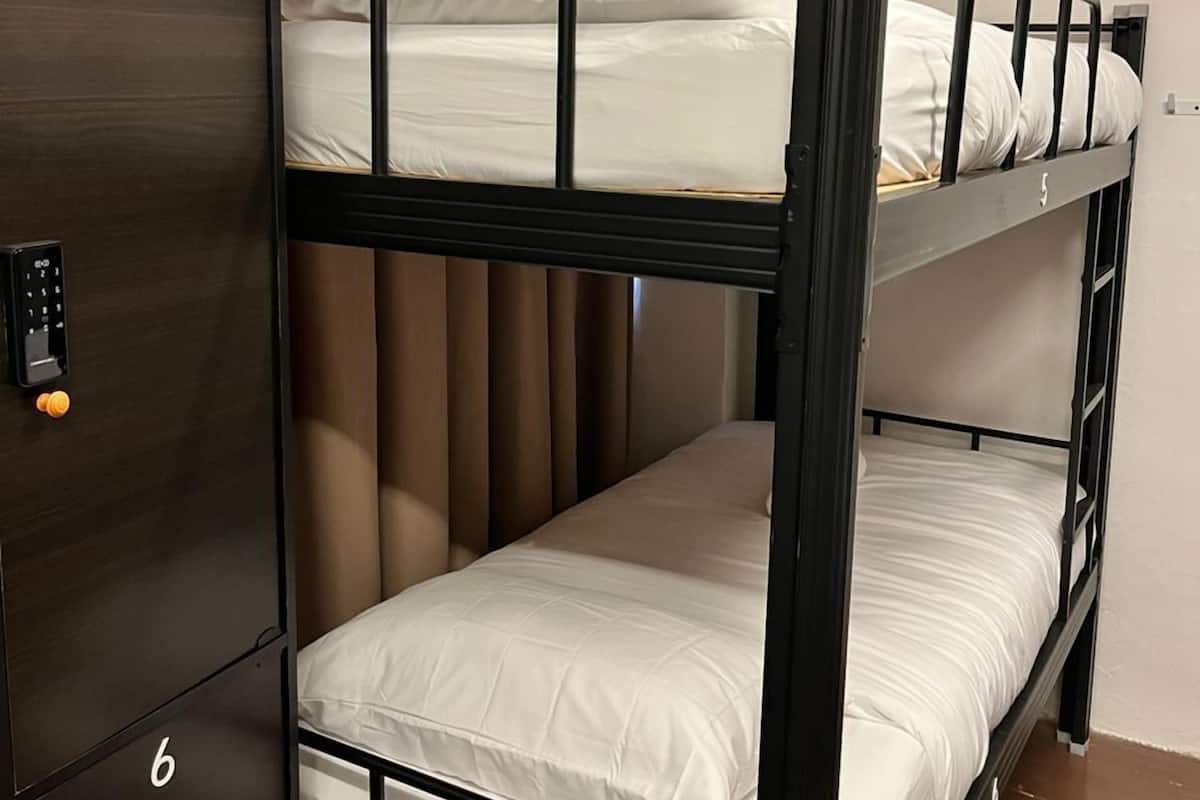 Een slaapkamer met een stapelbed, een kledingkast en een bedieningspaneel.