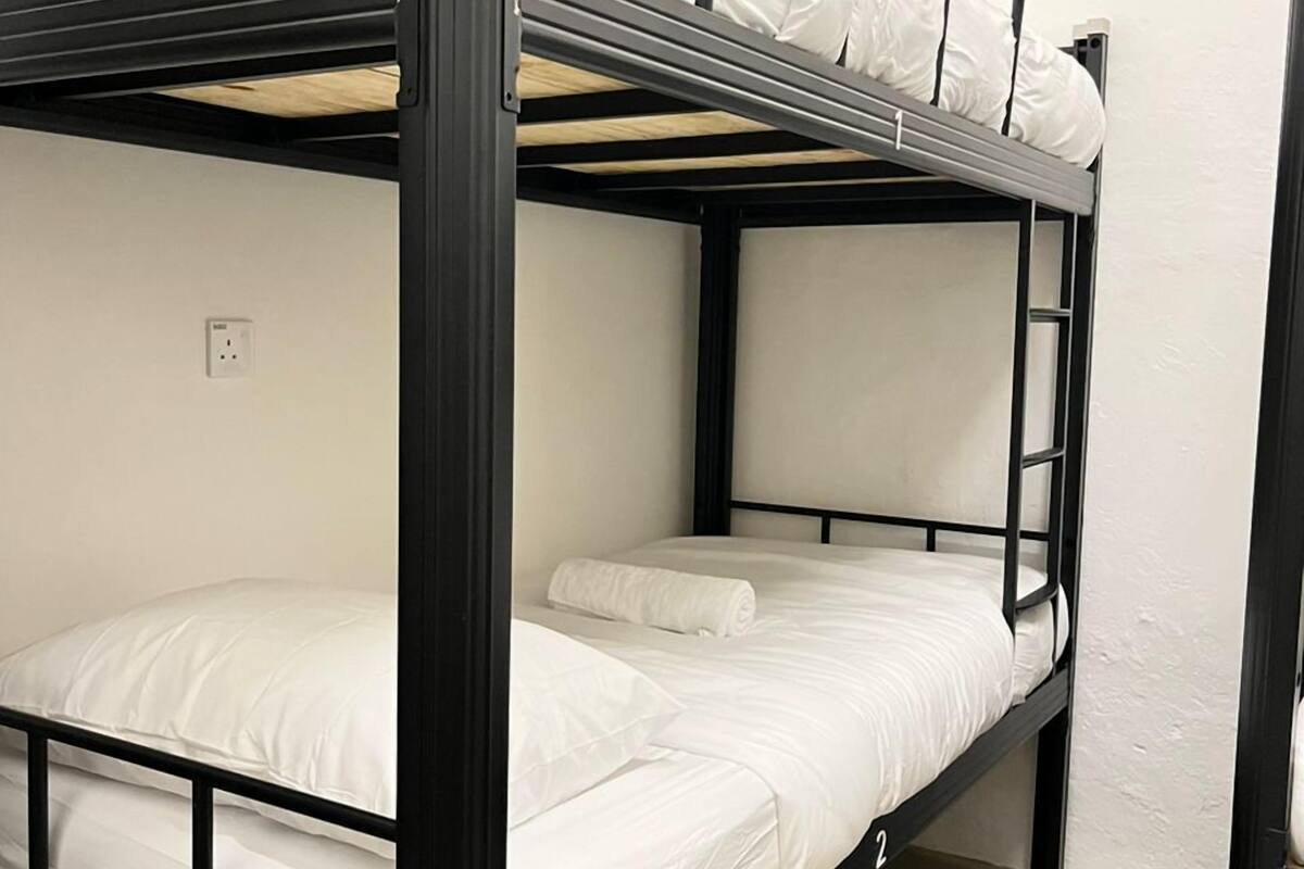 Een stapelbed met witte beddengoed en een metalen frame.