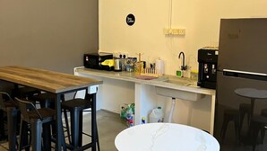 A compact kitchen with a wooden table, bar stools, a white round table, and a refrigerator. - Pine Armenian (George Town)
