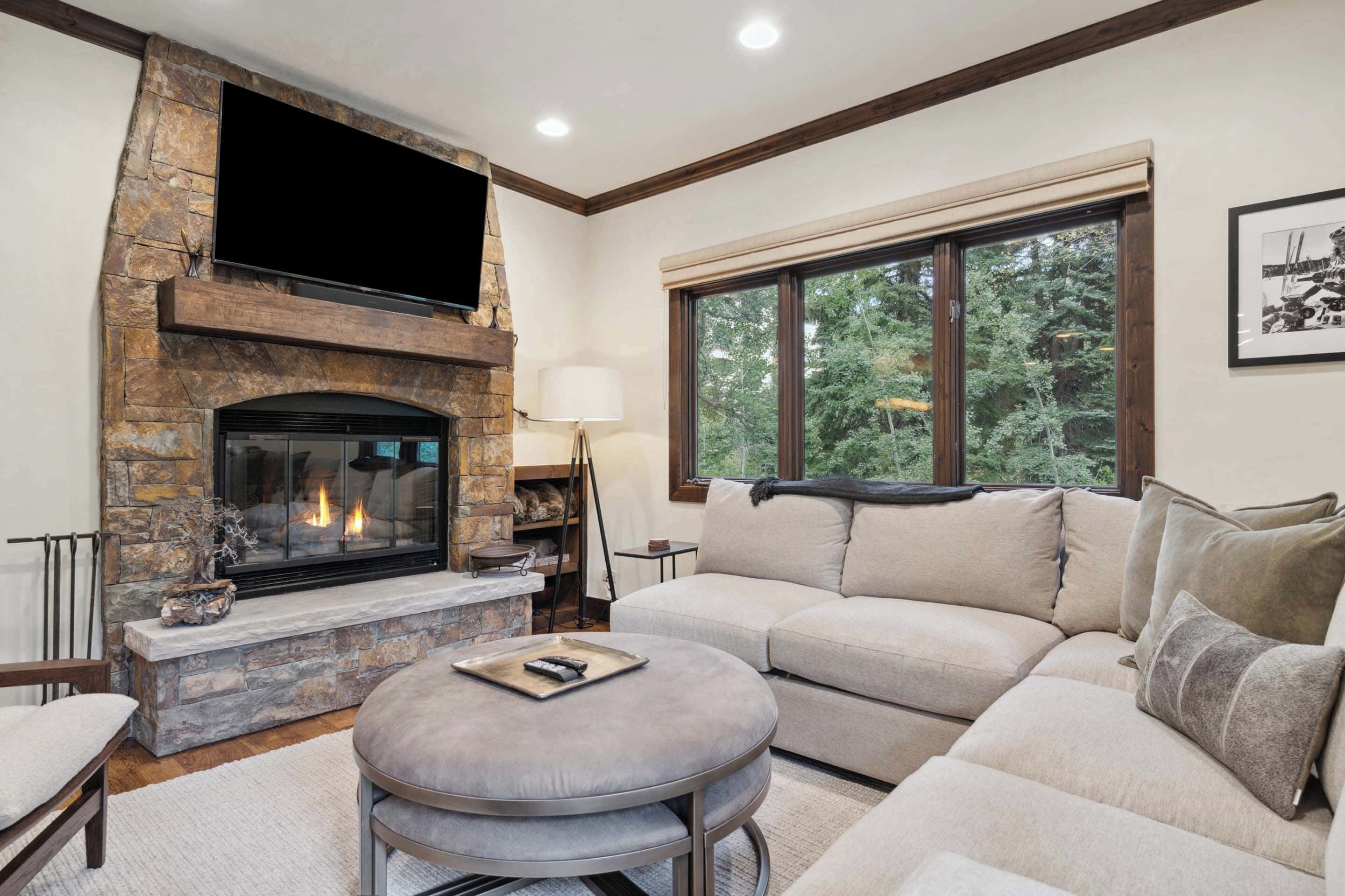 Un salon avec une cheminée en pierre, une grande fenêtre et un canapé.