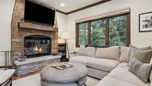 A living room with a stone fireplace, a large window, and a sofa. - The Charter at Beaver Creek C1105 (Beaver Creek)
