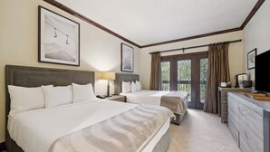 Une chambre d’hôtel avec deux lits, un bureau, une télévision et une fenêtre avec des rideaux.