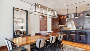 A modern kitchen with dark cabinetry, a wooden dining table, and a large bowl centerpiece. - Solaris 6G East - 4 Bedroom (Vail)