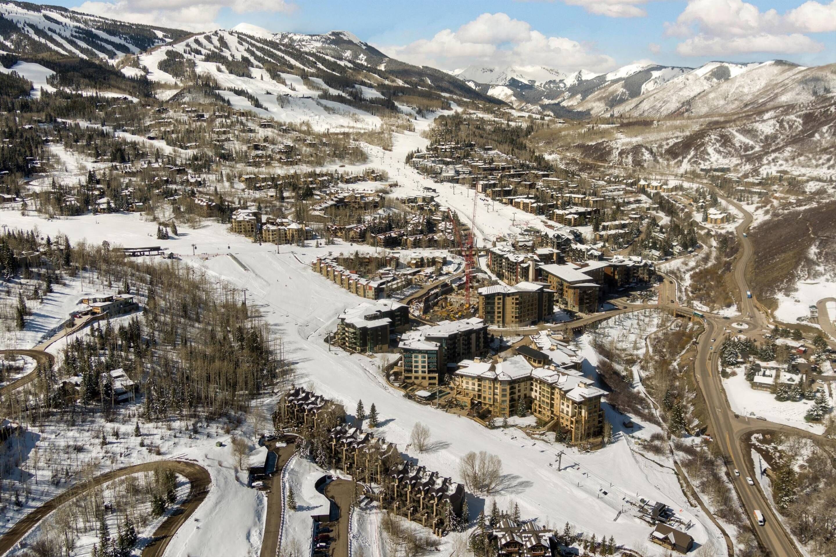 A snow-covered mountain town with a central cluster of buildings, roads, and ski slopes.