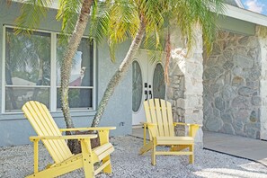 Two yellow Adirondack chairs outside a building with a stone facade and a window.