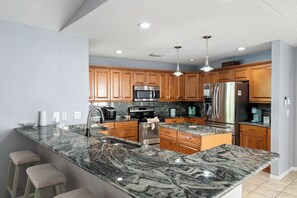 A modern kitchen with granite countertops, stainless steel appliances, and wooden cabinets.