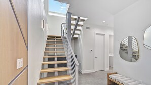 A modern interior with a wooden staircase, a bench, and a round mirror on the wall. - Luxury Home, Pool, Mins to Top Beaches and Downtown Sarasota (Sarasota)