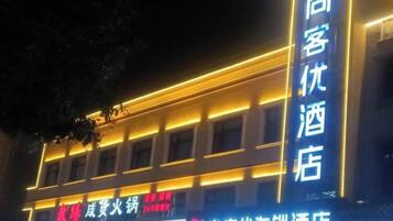 A hotel with illuminated signage, a prominent vertical sign, and a banner with text.