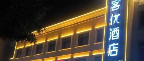 A hotel with illuminated signage, a prominent vertical sign, and a banner with text.