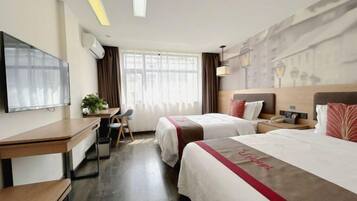 Habitación de hotel con dos camas, un escritorio, una silla, un televisor y una ventana con cortinas.