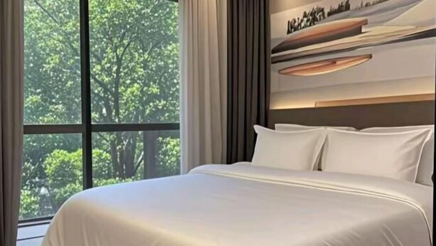 Un dormitorio moderno con un ventanal grande, una cama con ropa de cama blanca y una decoración minimalista.