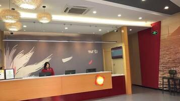 Una recepción con recepcionista, una pared con diseño de plumas y una pared de acento roja.