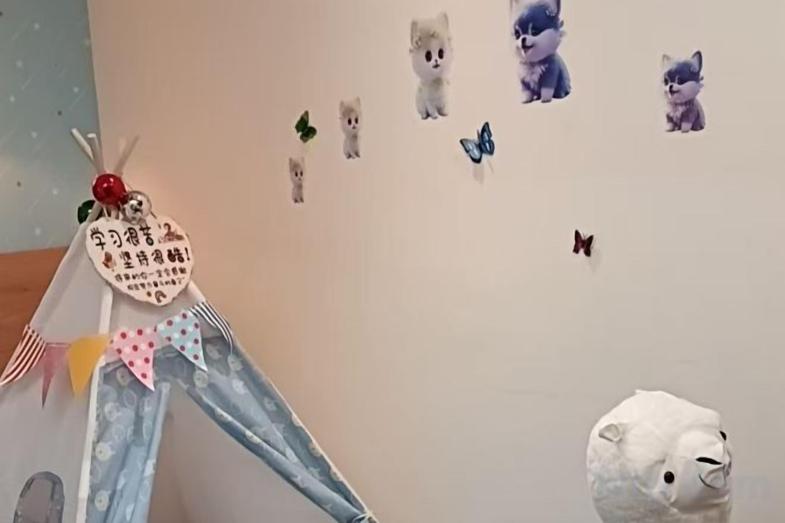 Una habitación con una estructura tipo tienda de campaña, decoraciones en la pared que incluyen pegatinas de animales y un peluche blanco.