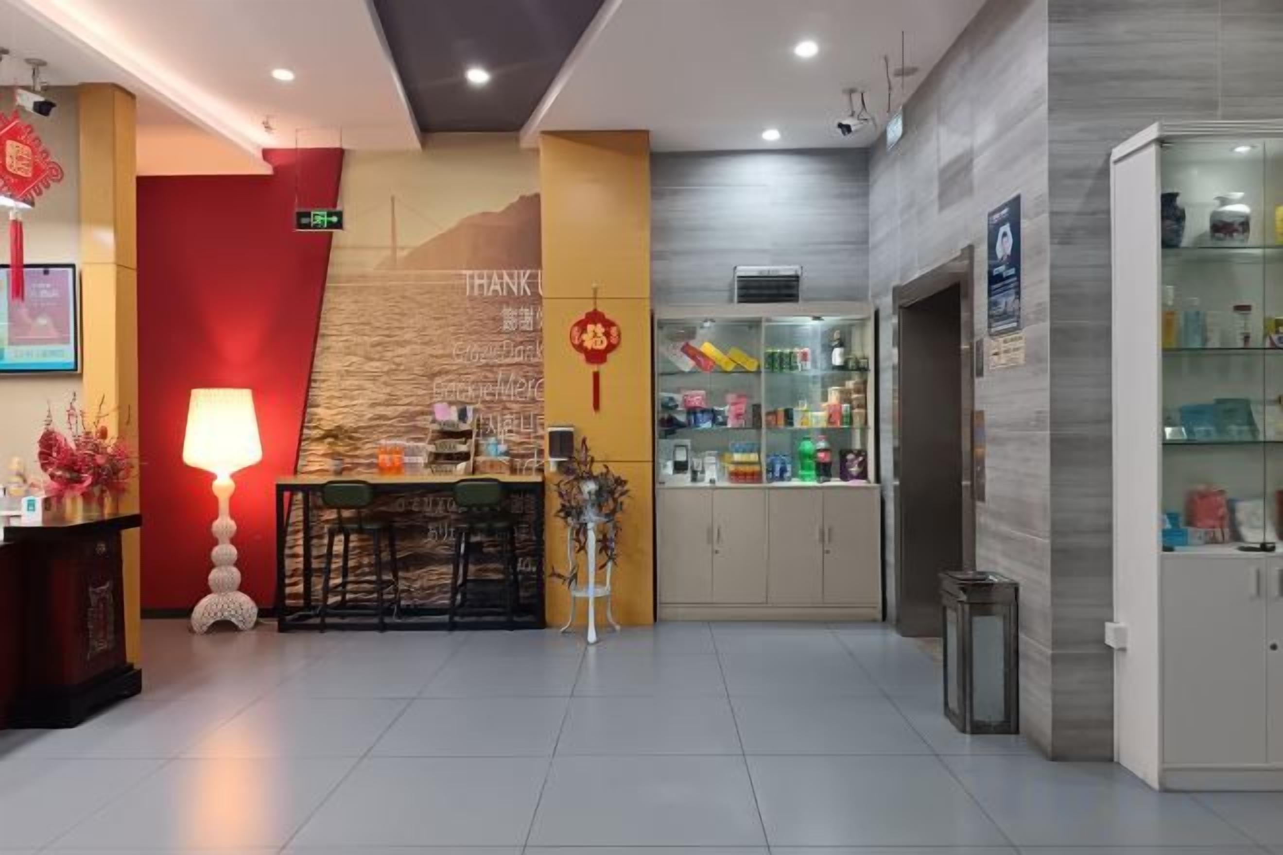 A hotel lobby with a reception desk, a wall-mounted information board, and a seating area.