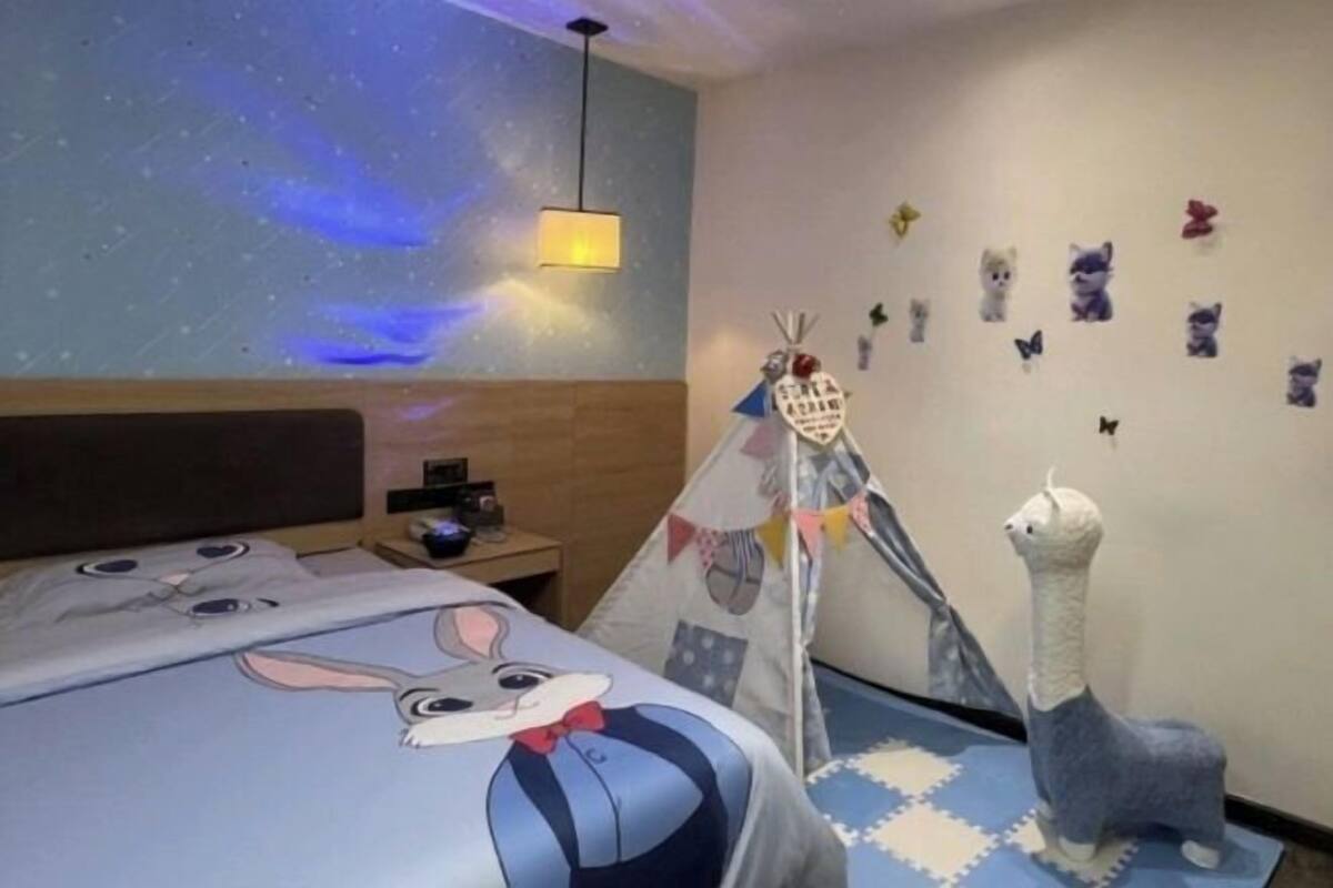 A room with a bed featuring a cartoon character design, a tent decoration, and a stuffed llama toy.