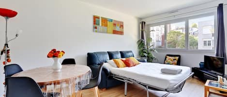 A compact living space with a bed, a dining table, and a TV.