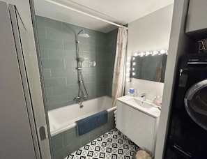 A bathroom with a bathtub, a shower, a sink, and a mirror with lights. - 3-bedroom family apartment Eiffel Tower balcony 15min (Paris)