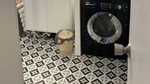 A compact bathroom with a sink, mirror, and two stacked washing machines.