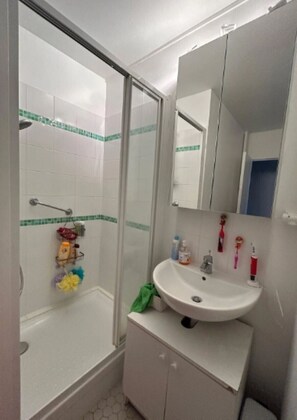 A bathroom with a shower, a sink, a mirror, and a cabinet.