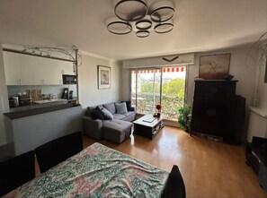 Ein modernes Wohnzimmer mit grauem Sofa, einem Couchtisch und einem Essbereich mit gemustertem Tischläufer.