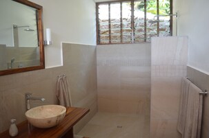A bathroom with a large mirror, a wooden vanity, a sink, a towel rack, and a shower area.
