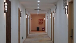 A hotel corridor with a carpeted floor, wooden doors, and wall-mounted light fixtures. - Yichun Yue Hotel (Yichun)