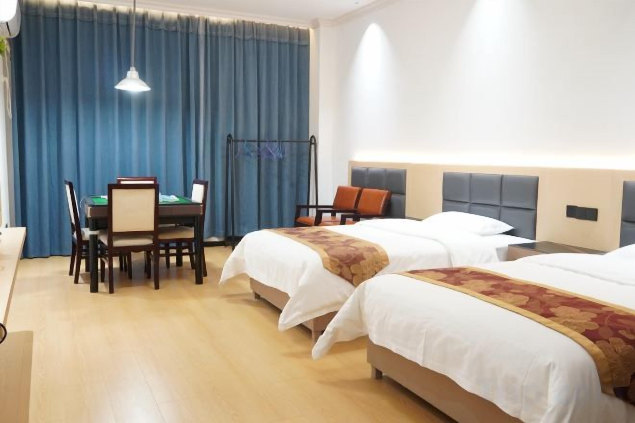 A hotel room with two beds, a desk, and a chair.