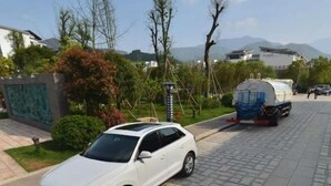 A white car parked on a paved road with a tanker truck in the background. - Yichun Yue Hotel (Yichun)
