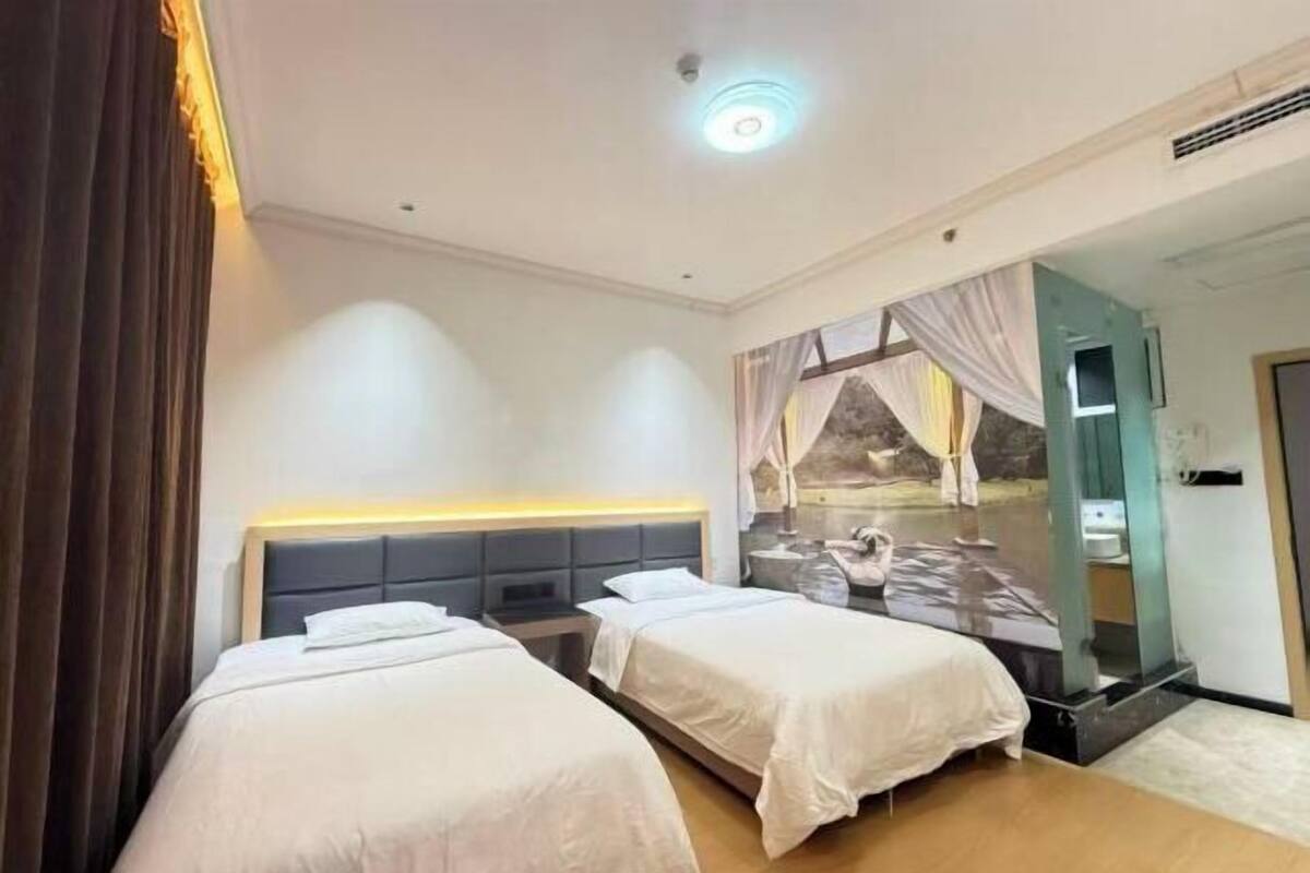 A hotel room with two beds, a large mirror, and a view of a rocky landscape.