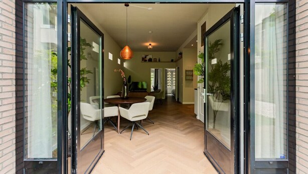 Um interior moderno com área de jantar, portas de vidro e piso em padrão herringbone.