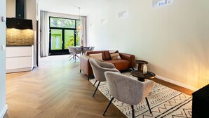 Uma sala de estar moderna com um sofá, duas poltronas, uma mesa de centro e uma lareira.