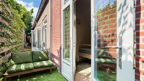 Ein kleiner, privater Garten mit einem grünen Sofa und einer Holzbank.