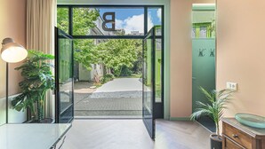 Ein moderner Hotelzugang mit Glastür, einem Blumentopf und Blick auf die Straße.