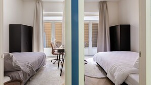 Et hotelværelse med to senge, et skrivebord og en stol.