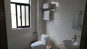 Un baño con inodoro, un lavabo, una ventana con barrotes y una ducha.