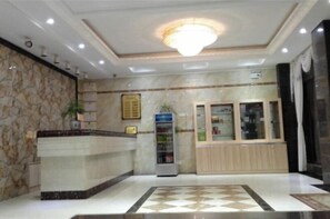 A reception area with a marble reception desk, a glass display cabinet, and a vending machine. - Fangxian Shuyue Business Hotel (Fang County)