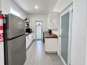 A compact kitchen with a refrigerator, a microwave, and a sink.