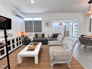 A modern living room with a sofa, chairs, a coffee table, and a dining area with a round table.