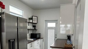 A modern kitchen with stainless steel appliances, white cabinetry, and a tiled floor. - Serenity House on Isla Verde Beach (Carolina)