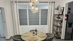 A dining area with a round table, four chairs, and a chandelier. - Serenity House on Isla Verde Beach (Carolina)