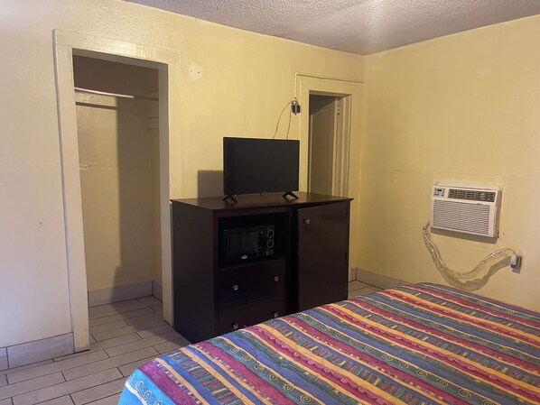 Une chambre à coucher comprenant un lit, une commode, un téléviseur et un appareil de climatisation.