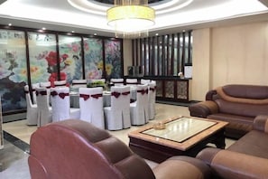 Un área de descanso moderna con mesas redondas, sofás de cuero y una lámpara decorativa.