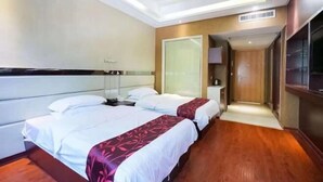 Habitación de hotel con dos camas, un espejo grande, televisión y suelo de madera.